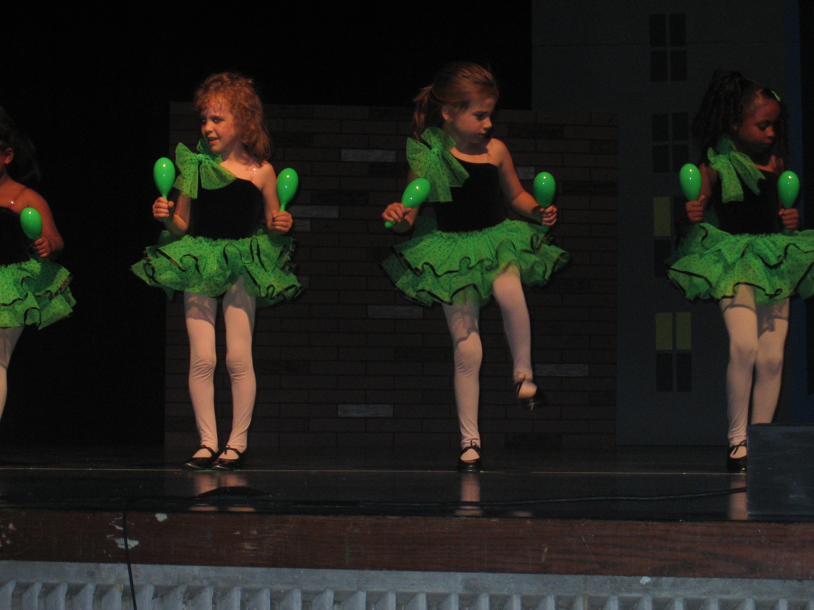 Little Kate is on stage tap dancing in a glow in the dark tutu while shaking Maracas.