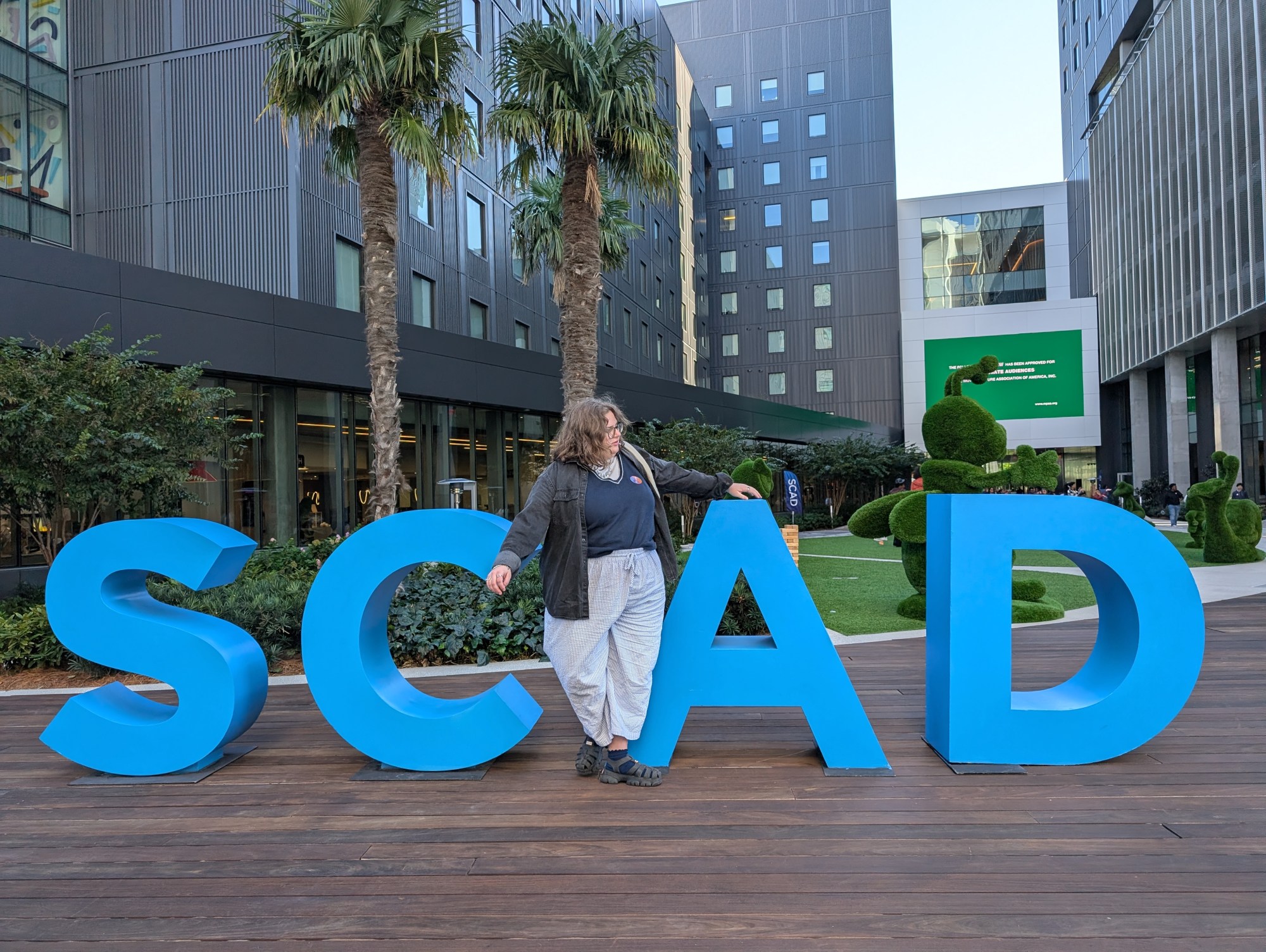 Kate poses with big blue letters spelling SCAD.